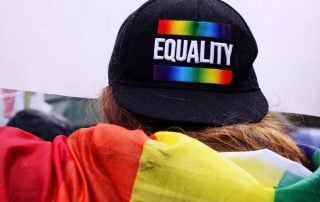 Back of head of someone wearing a Pride Equality baseball cap