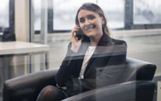Woman seen through glass panel sat speaking on phone