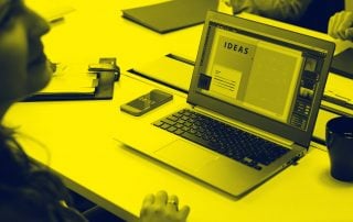 Woman sat at boardroom table in front of laptop