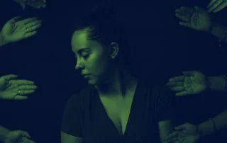 Woman looking away as numerous hands extend out to her