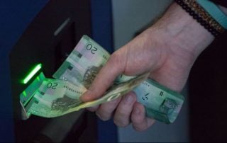 Man receiving stack of $20 from ATM