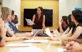 Woman head boardroom meeting while reading paper