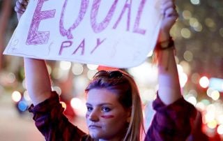 Woman holding sign reading "Equal Pay"