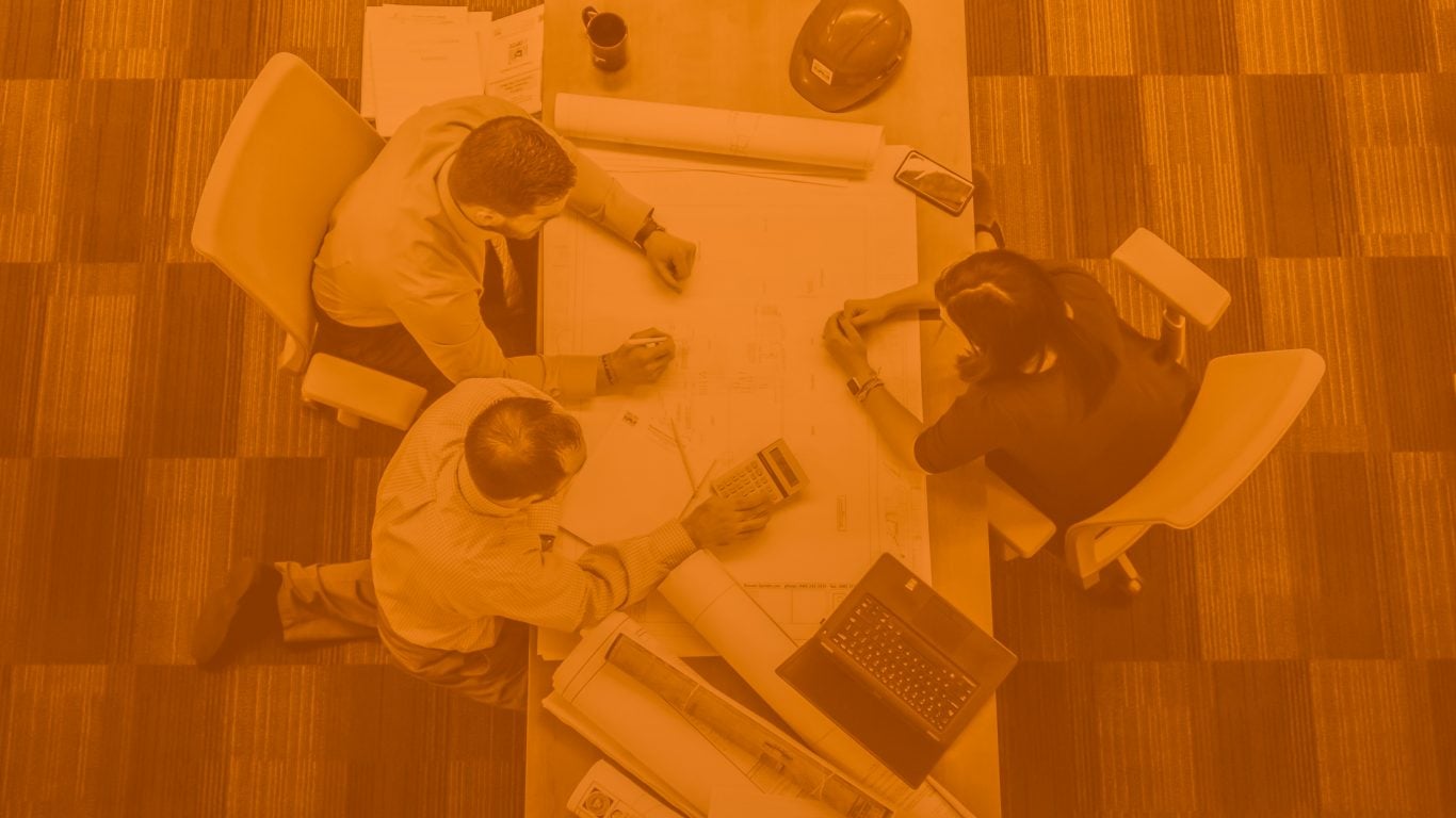 Overhead shot of two men and one woman overlooking strategy