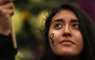 Close up on woman with female icon painted on her right cheek