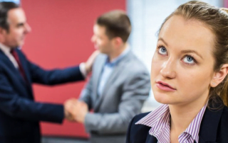 Woman in foreground rolling her eyes and two men in background shaking hands