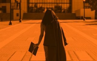 Graduate walking away from camera with convocation hat in hand