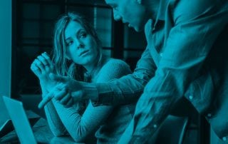 Woman seated at her computer looking up at male colleague