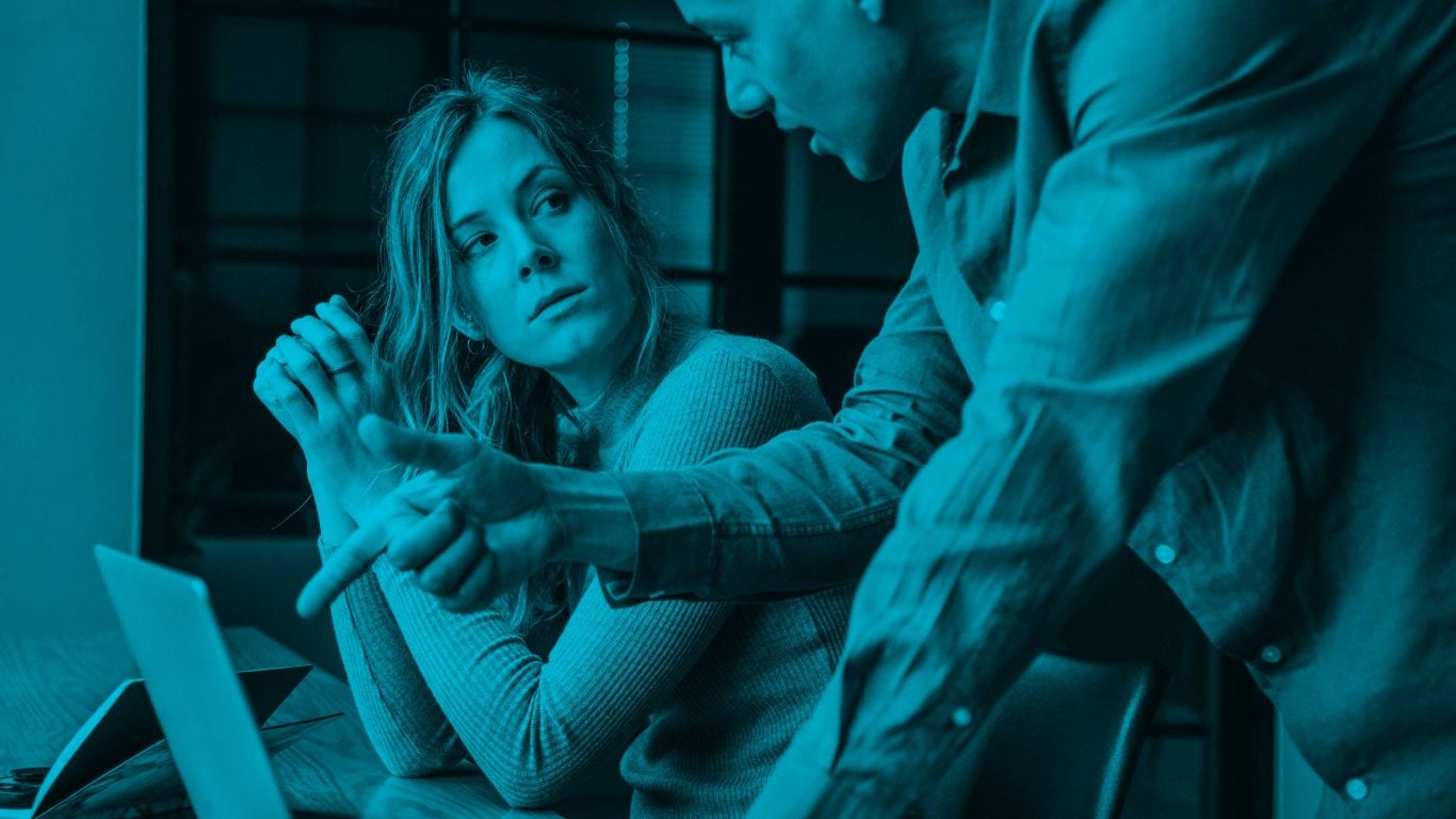 Woman seated at her computer looking up at male colleague