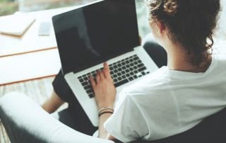 Woman seated on a chair with a laptop on her lap