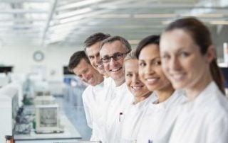 A group of scientists looking at the camera smiling in a lab