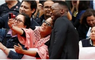 Mahershala Ali poses with fans while taking a photo