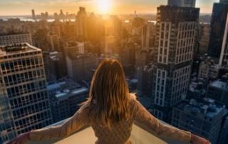 A woman holding out her arms facing the cityscape