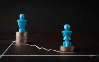 A male and female chess piece place on a stack of coins, with the male token raised higher