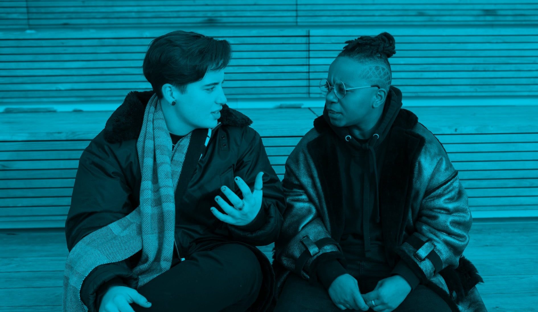 Two transmasculine people sitting together and having a serious conversation