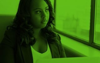 Woman seated in front of laptop, looking outside of window