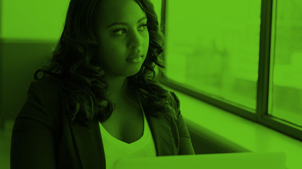 Woman seated in front of laptop, looking outside of window