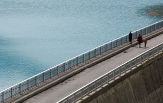 Three people walking on a bridge