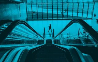 View from top of the escalator with a woman walking by at the bottom