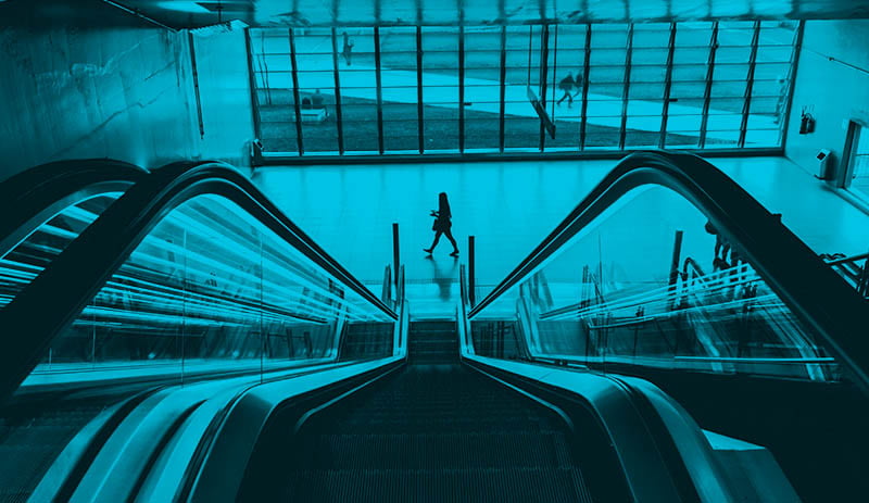 View from top of the escalator with a woman walking by at the bottom