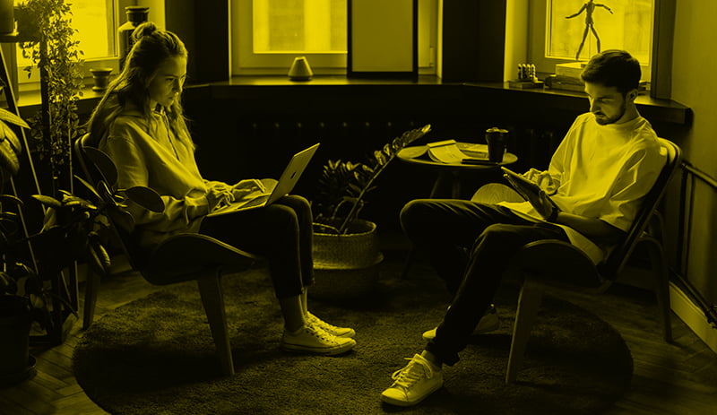 Woman and man sat in home chairs working