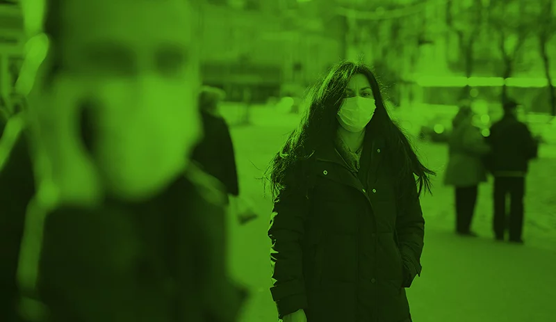 Close Up of Man wearing a face mask with a women in background wearing facemask