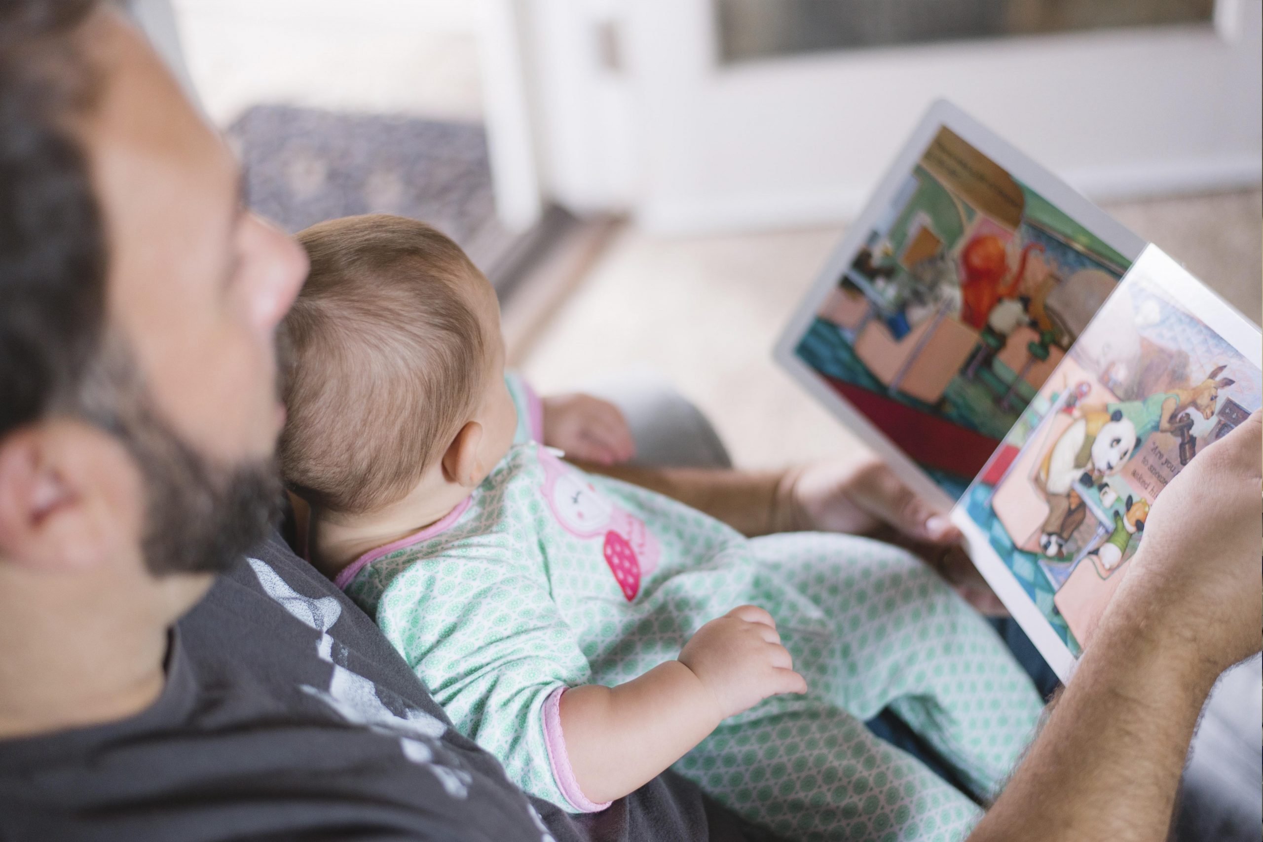 Father holding toddler reading a book
