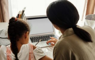 Mother and daughter homeschooling in front of laptop