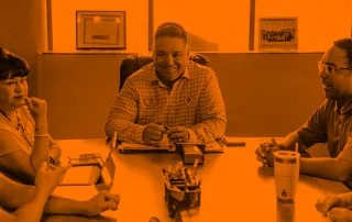 Three colleagues sat at end of board table