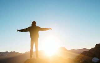 Man standing in front on a sunset on mountaintop