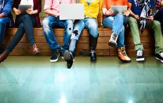 Group of people sat on a bench. Photo cropped at their shoulder