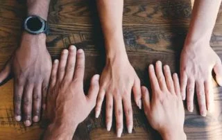 Multi racial hands spread across a table