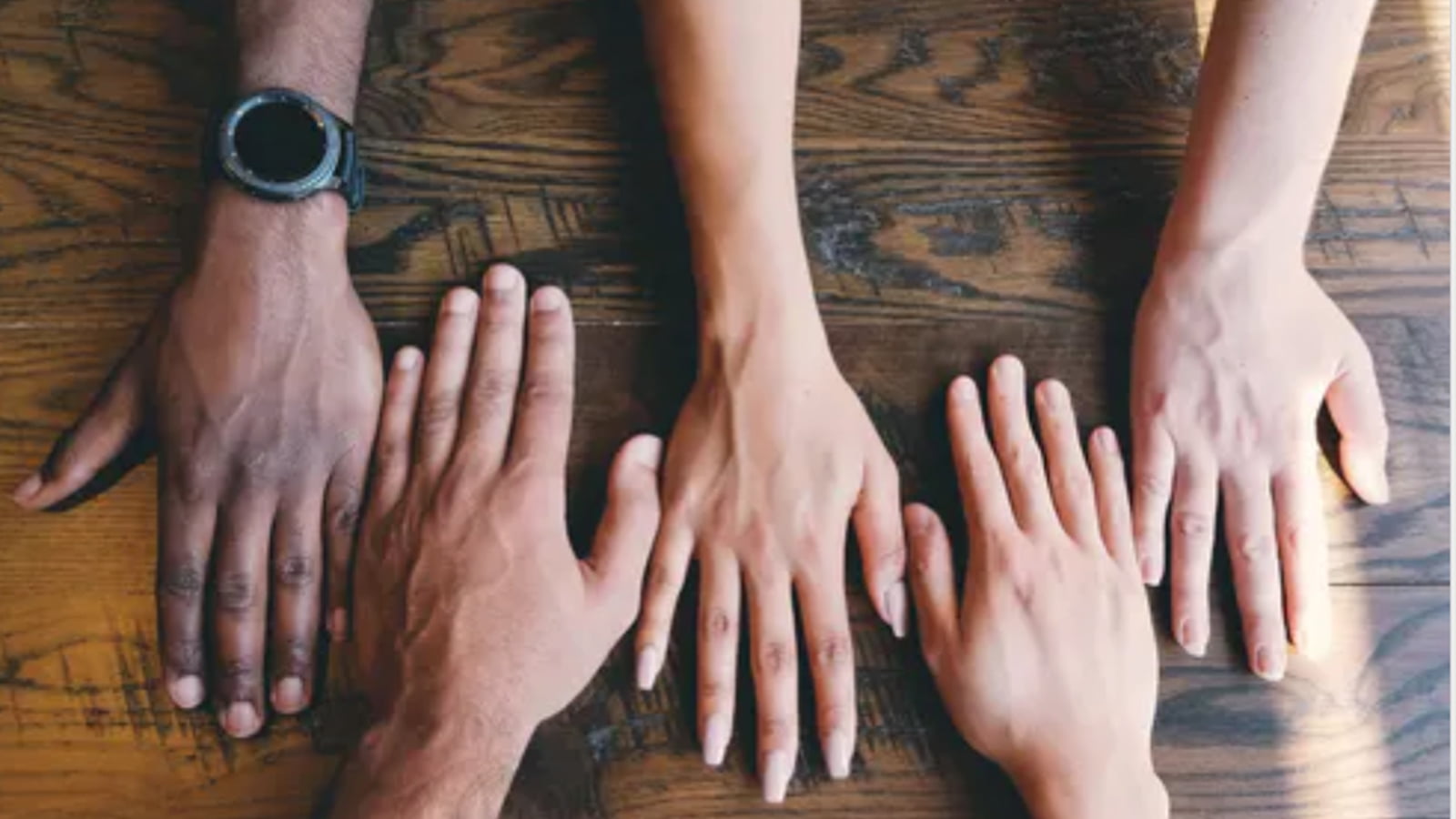 Multi racial hands spread across a table