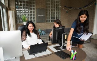 Woman working at her home office while her two daughters assist