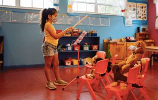 Young girl in face mask conducting music in an empty classroom