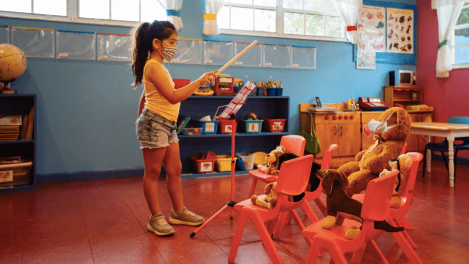 Young girl in face mask conducting music in an empty classroom