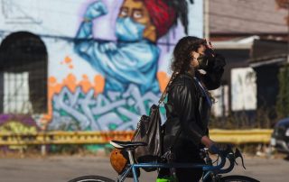 Woman wearing mask walking with bike