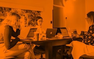 Office with three women sat at desk with their laptops