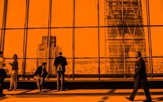 Long shot of building hallway with populated with several people, overlooking cityscape.