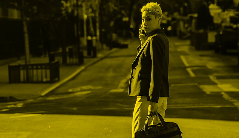 Woman walking across the street with cellphone in hand