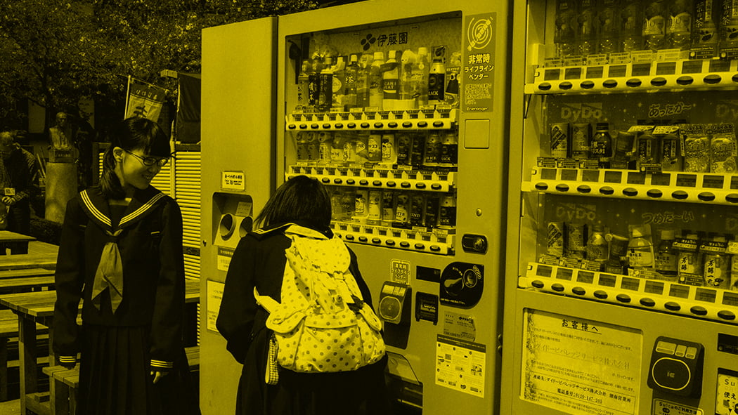 Two school girls looking at vending machine