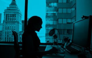 Silhouette of woman sat at computer desk in business office