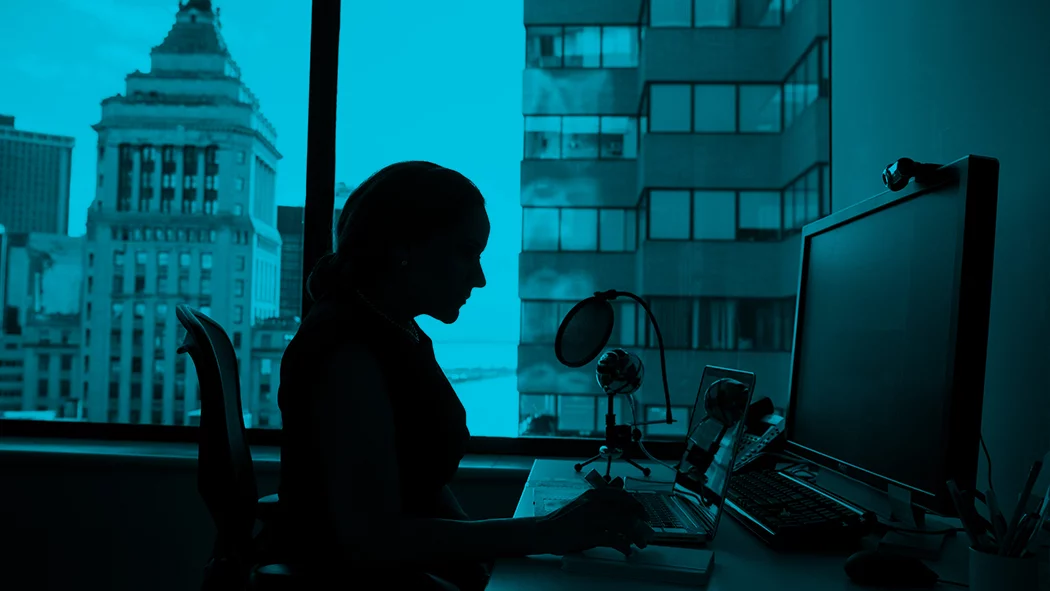 Silhouette of woman sat at computer desk in business office