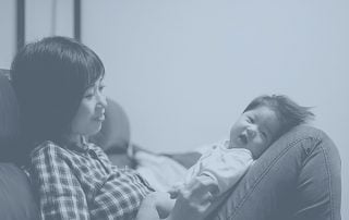 Mother sat on couch holding baby in her lap