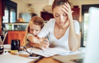 Woman sat at desk working with child hold on to her arm