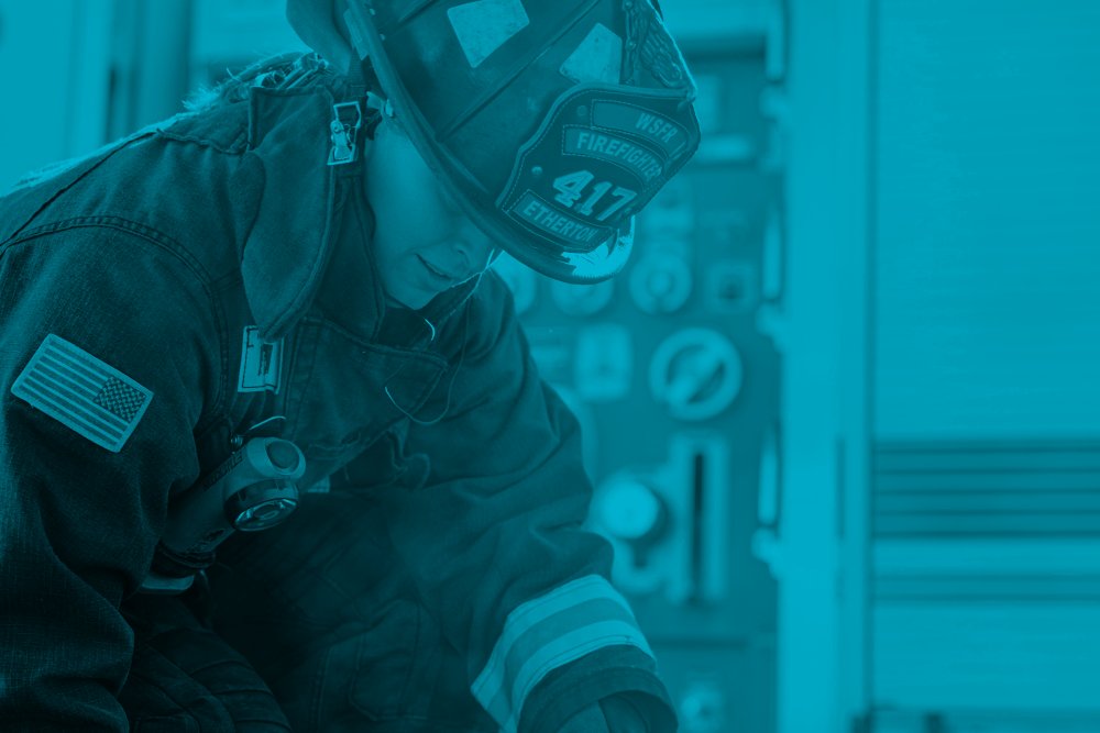 A woman firefighter is working next to a fire truck. Credit: Logan Weaver