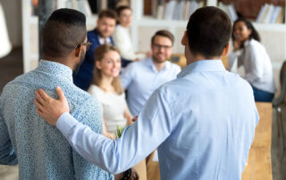 two employees shaking hands in a workplace setting