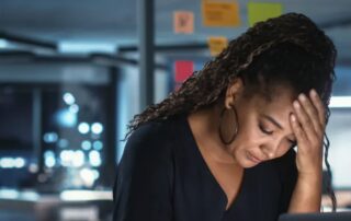 woman in office looking down at her desk with a distressed expression on her face