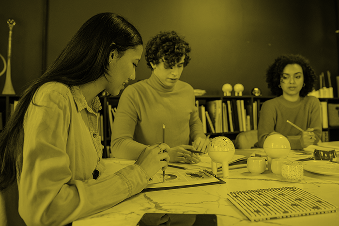 three people sitting across a desk having a meeting